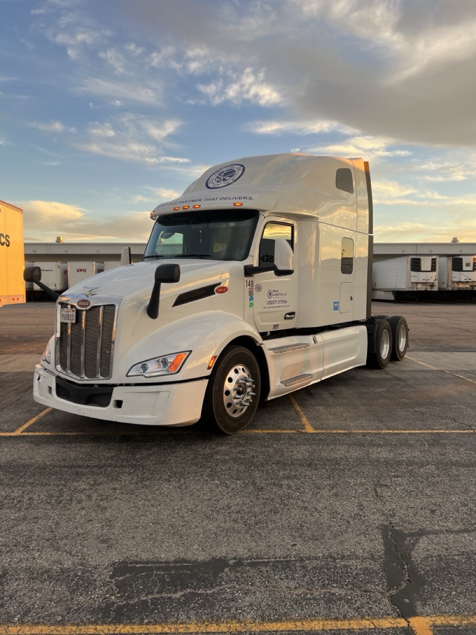 Maas Logistics Peterbilt sleeper tractor parked at a distribution center at sunset